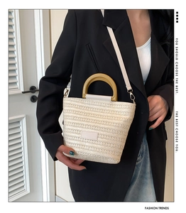 Détail d'un sac cabas tissé beige avec poignée rigide marron et fine bandoulière