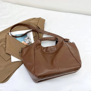 Detail view of deep brown leather tote bag with vertical stitching and shoulder strap