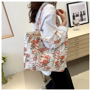 Dettaglio della borsa tote in tela con stampe floreali rosse vintage su sfondo color crema
