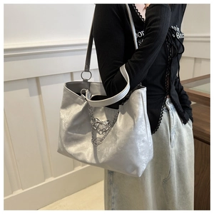 Détail du grand sac cabas argenté avec chaîne métallique et breloque en forme de nœud