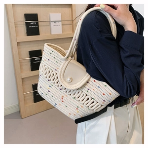 Detail of crochet straw beach bag featuring colorful polka dots and a large pearl clasp
