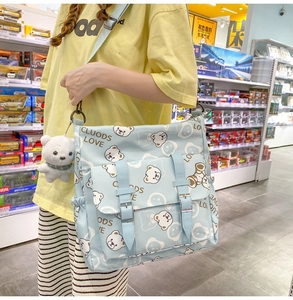 Detail of light blue nylon crossbody bag with cartoon bear prints and plush charm