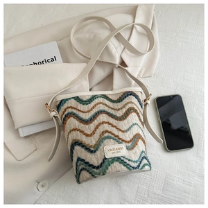 Close-up of woven bucket bag with wave patterns and an adjustable beige shoulder strap