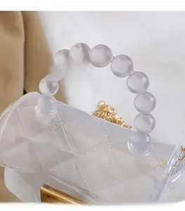 Détail du sac en gelée transparent avec motif de losanges et poignée perlée