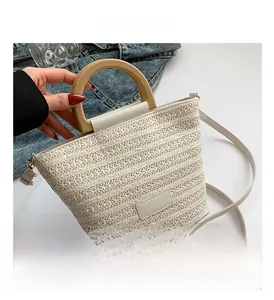 Détail d'un sac seau tissé crème avec poignée en bois et finitions en similicuir