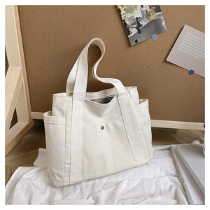 Detail of a white canvas tote bag with multi-pocket design and metal snap button closure