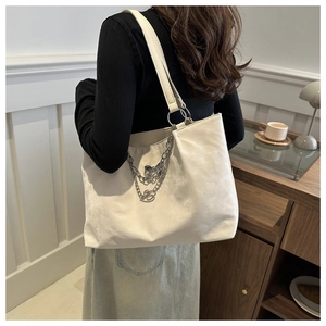 Détail du sac cabas blanc avec breloques papillon en argent sur la bandoulière