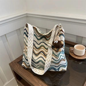 Detail view of woven velvet tote with blue and brown wave patterns and plush charm