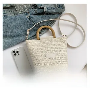 Détail du sac seau tissé blanc avec poignées en bois et empiècement en cuir élégant