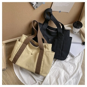 Close-up of beige and black canvas tote bags with side pockets and magnetic closure