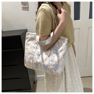 Dettaglio di una borsa tote grande in tela floreale che mostra la stampa e i doppi manici