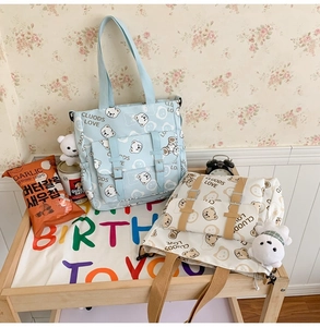 Detail of blue and white canvas tote bags with cute bear prints and adjustable buckles