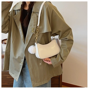 Close-up of white crocodile pattern crescent bag with metal chain and fur ball charm