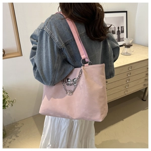 Sac fourre-tout rose avec chaîne argentée et détail de nœud porté par un mannequin