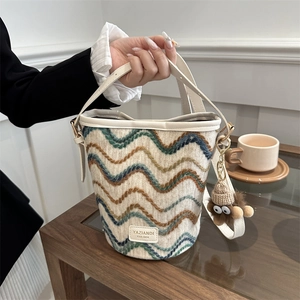 Detail of woven bucket bag with multi-color wave patterns and plush doll charm