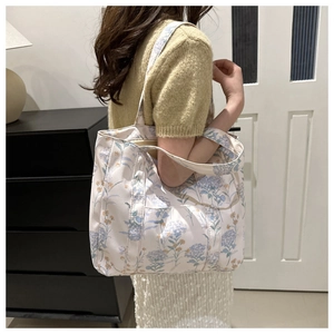 Dettaglio della borsa tote in tela con motivi botanici stampati in blu e giallo zenzero