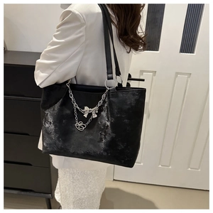 Grand sac cabas noir en PU avec chaîne argentée et breloque nœud porté par un mannequin