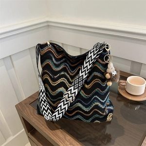 Detail of colorful wavy knit tote bag with thick strap and plush monster charm