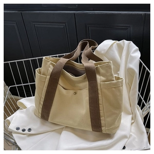 Detail view of large canvas tote bag featuring side pockets and sturdy brown woven handles