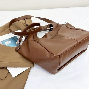 Macro shot of brown PU leather tote bag details with wide strap and metallic rings