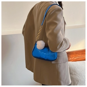 Detail of blue faux snake-skin crescent bag with gold chain and white fur ball charm