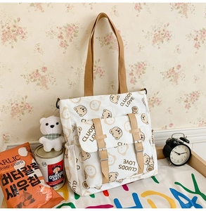 Close-up of white canvas tote bag with cartoon bear prints and functional multi-pockets