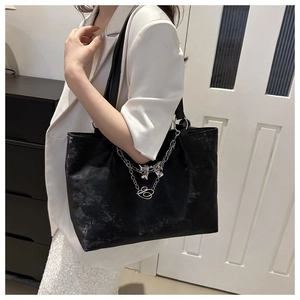 Détail d'un cabas noir avec chaîne argentée et pendentif C sur cuir texturé
