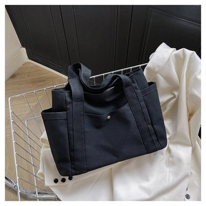 Detailed macro view of black canvas tote bag with metal snap pocket on its front
