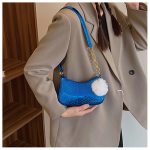 Detail of blue metallic faux snake skin shoulder bag with gold chain and white fur pompom