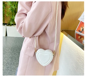 Detalle del bolso bandolera blanco en forma de corazón con elegante cadena de perlas