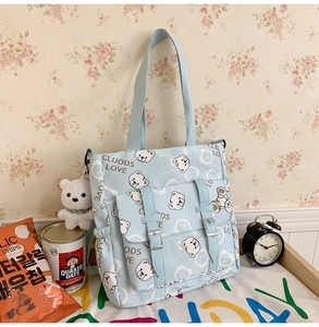 Detail of light blue cartoon tote bag with bear print and buckle pocket for students
