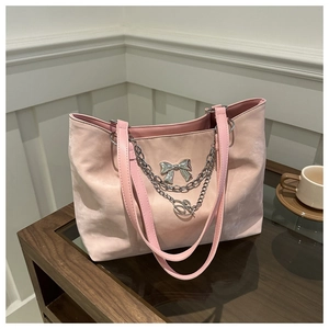 Vue détaillée du sac cabas en daim rose avec chaîne argentée et pendentif papillon