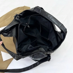 Interior view of black faux leather tote bag showing lining and multi-functional pockets