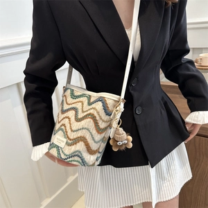 Detailed view of striped crochet bucket bag with colorful wavy pattern and brand label
