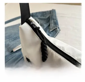 Details eines glatten schwarzen Reißverschlusses an einer weißen Nylon-Tragetasche
