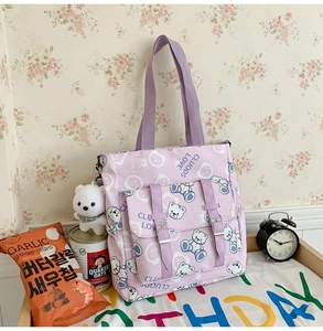 Detail view of purple nylon tote bag featuring cute bear print and plush bear keychain pendant