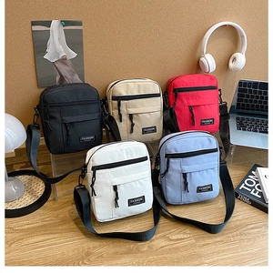 Close-up of five colorful nylon crossbody bags with adjustable straps in a modern desk setting