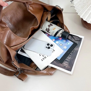 Spacious interior of a brown faux leather tote bag holding a tablet and daily essentials