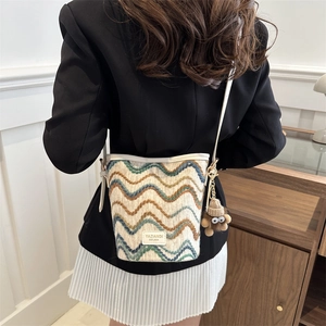 Detail of woven bucket bag with wave pattern and cute plush monster charm accessory