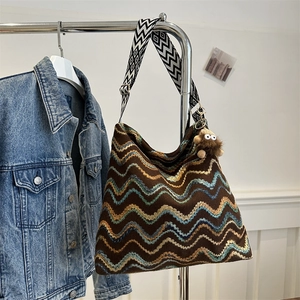 Detail of colorful striped woven velvet tote with geometric strap and monkey charm