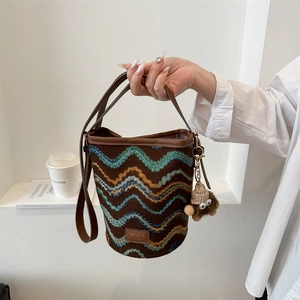 Detail of knitted bucket bag with colorful wavy patterns and premium leather handle