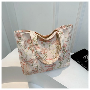 Dettaglio della borsa tote in tela color crema con motivi floreali rosa e manici