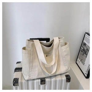 Detail view of cream canvas tote bag with side pockets and dual handles for travel