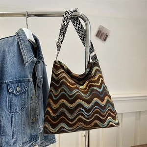 Close-up of bohemian woven tote bag showing detailed wave embroidery and chic strap texture