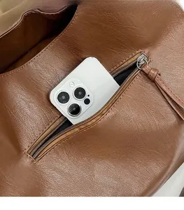 Detail of the exterior zip pocket on a brown tote bag holding a large smartphone