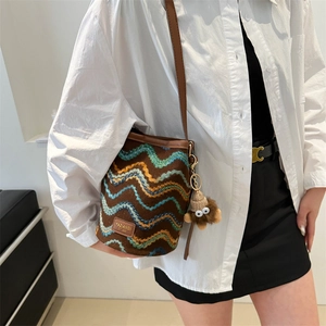 Detail shot of bohemian striped bucket bag with colorful embroidery and plush charm