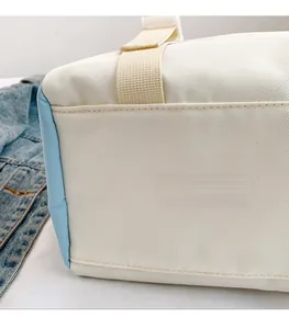 Detail of canvas shoulder bag showing durable beige fabric and light blue side panels