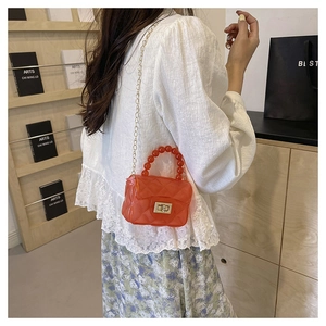 Détail du sac bandoulière orange avec texture matelassée, poignée en perles et chaîne