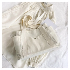 Detail view of large canvas tote bag with front snap pocket and reinforced woven handles