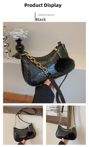 Detail of black faux snakeskin hobo bag with gold chain strap and plush pompom accessory